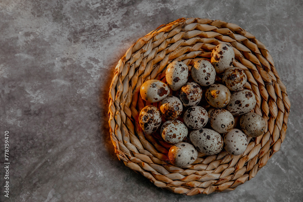 Wicker plate with quail eggs on a gray background
