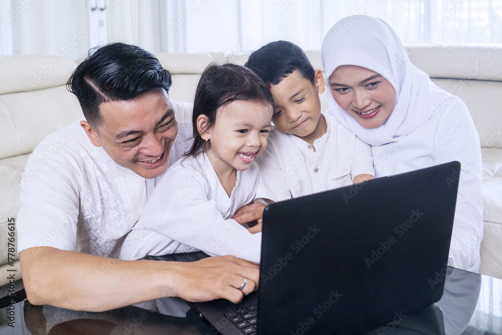 Happy muslim family of four using laptop watching streaming video Happy muslim family of four using laptop watching streaming video