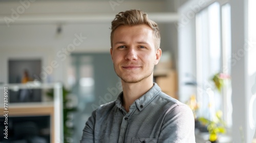 A casually dressed man smiling in an office with an indoor garden view photo