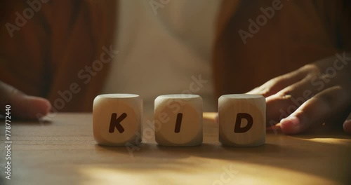 Hands of a child moves wooden block to making KID word concept photo