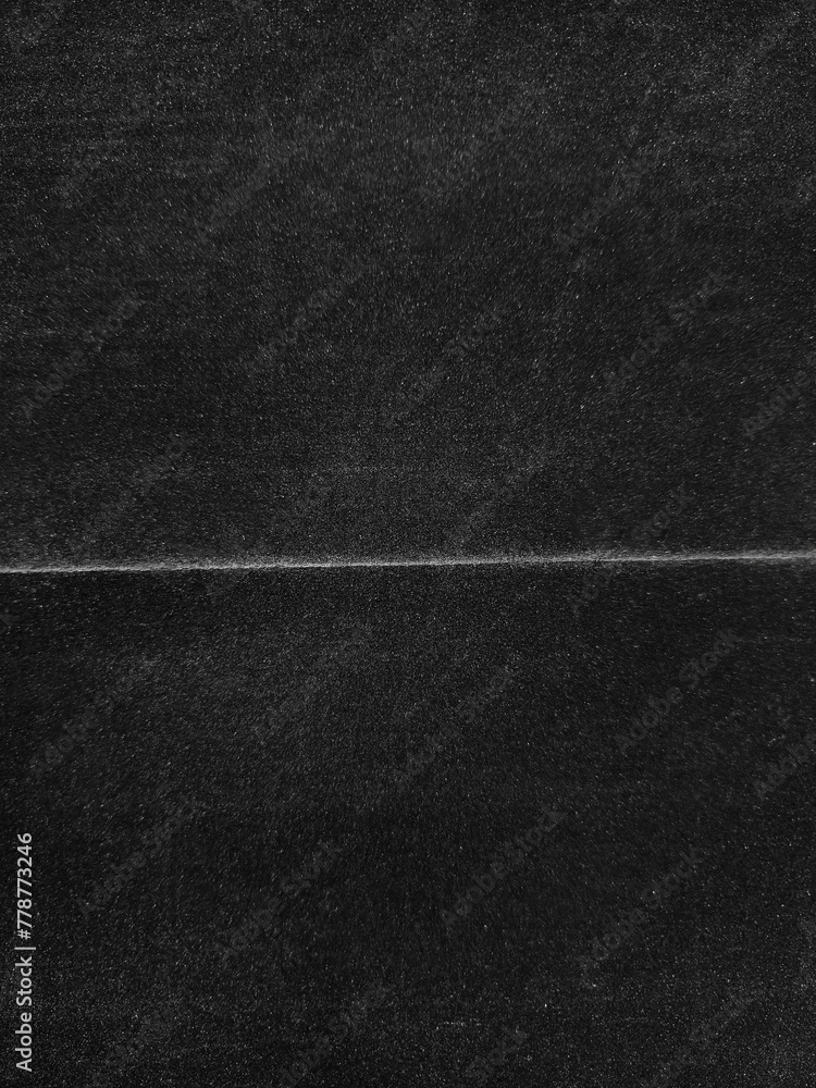 Abstract worn black background from crumpled paper. Old damaged surface with wrinkles and dust. Folded cardboard