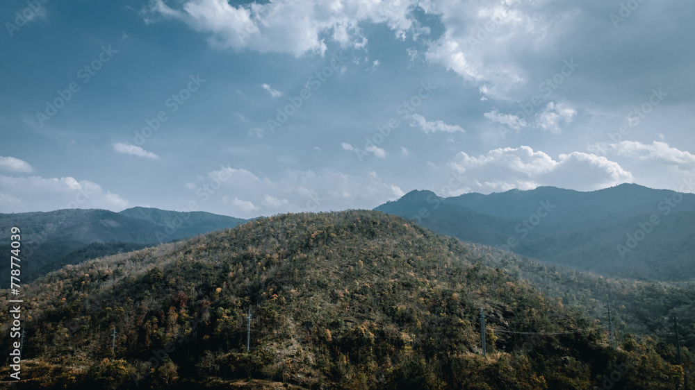 Mountains rise above a verdant valley as clouds float by in this panoramic summer landscape.