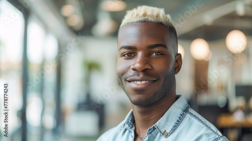 An indoor portrait of a smiling young man with stylish bleached hair in a well-lit contemporary setting photo