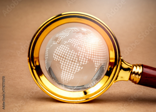 Global trends, world wide customer insights, digital online connection technology and business marketing, web browser concept. Close-up digital globe inside magnifying glass len on brown background.