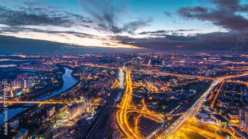Aerial top view of Moscow city day to night transition timelapse after sunset. From the observation platform of the business center of Moscow City. Moscow river and traffic on roads at summer evening photo