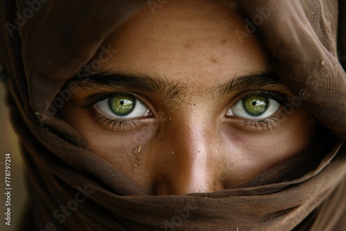 Close up of beautiful light green eyes and sad face under hijab