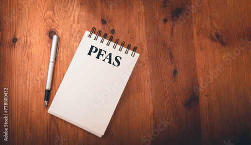 note pad on wooden table  with pfas, per- and polyfluoroalkyl substances , concept of eternal or forever chemicals and pollution ,copy space . © robert