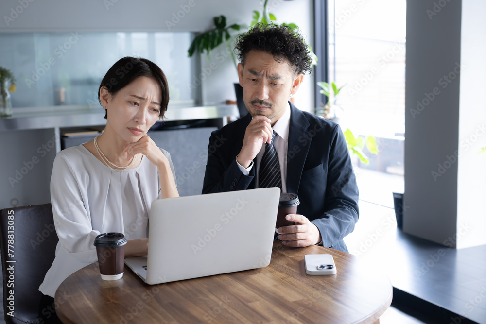 Obraz premium パソコンを見ながら業績やit化(dx)に悩む男女のビジネスシーン