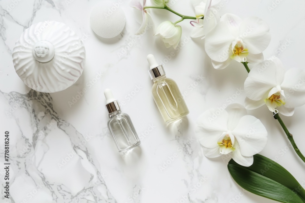 Top-view shot of a white marble countertop with a clear glass bottle of essential oil, a single white orchid, and a minimalist diffuser