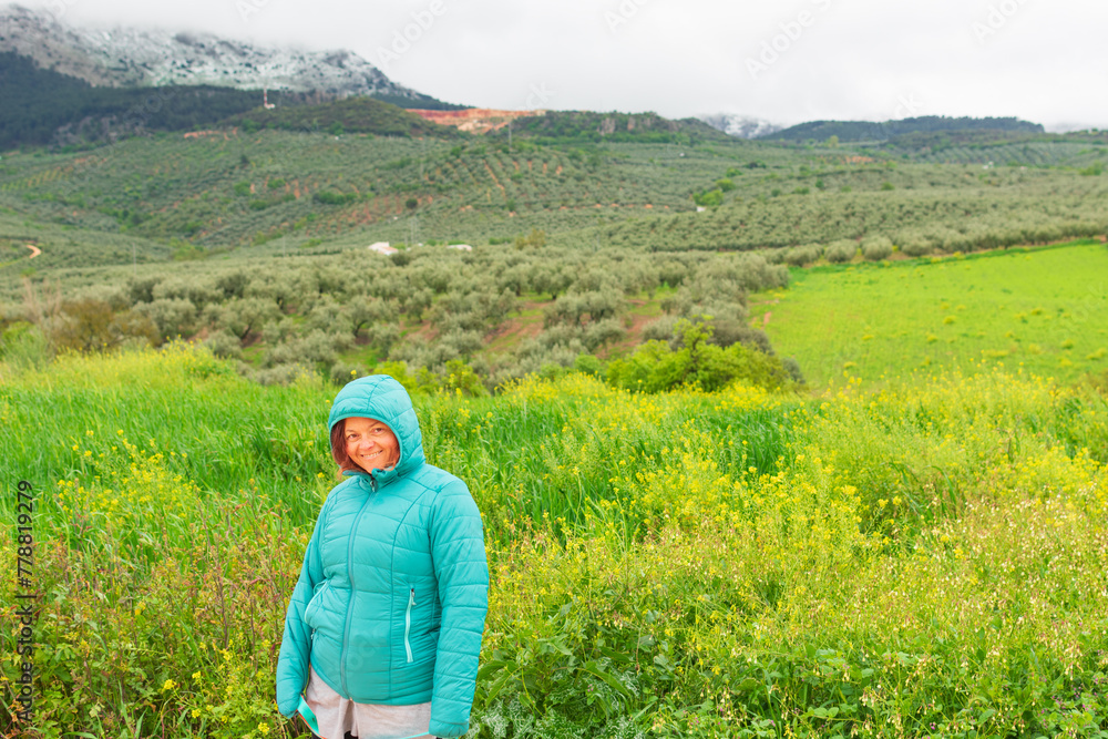 hiker poses for the camera smiling, with the green and flowered meadow in granada