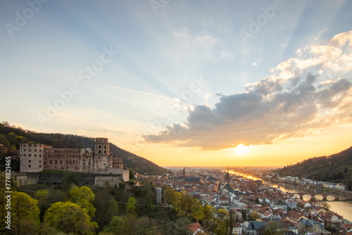 View over an old town with a castle or palace rune in the evening at sunset. This place is located in a river valley of the Neckar  surrounded by hills. Heidelberg  Baden-W  rttemberg  Germany