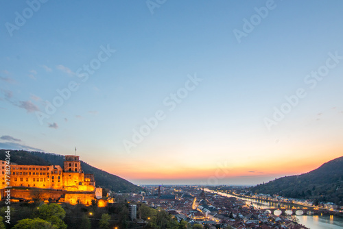 View over an old town with a castle or palace rune in the evening at sunset. This place is located in a river valley of the Neckar, surrounded by hills. Heidelberg, Baden-Württemberg, Germany