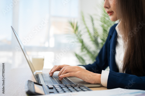 Portrait of smiling beautiful business asian woman at modern office desk using laptop to work and write notes, Business people employee freelance online marketing e-commerce telemarketing concept.