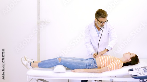 Tableau sur toile Doctor auscultating the patient's abdomen with a stethoscope