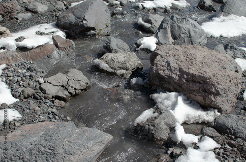 the melted snow flows down in a stream among the rocks in the mountains