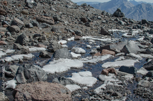 the melted snow flows down in a stream among the rocks in the mountains