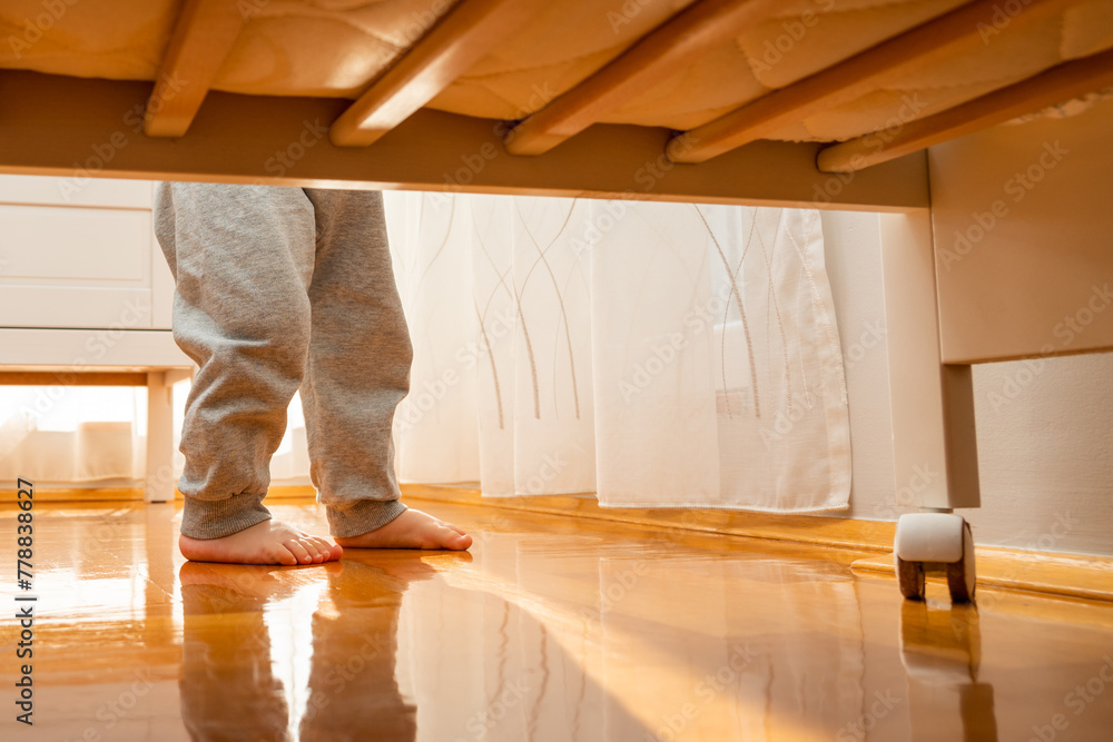 Baby walking barefoot to a crib photographed from the floor. Hidden frame concept Baby walking barefoot to a crib photographed from the floor. Hidden frame concept