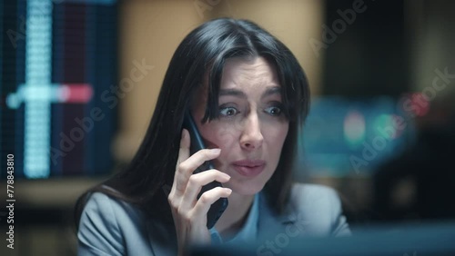 Portrait of beautiful Caucasian worker talking with her client or colleague on phone. Young woman having stressed conversation on smartphone while looking at computer screen. Disappointment at work.