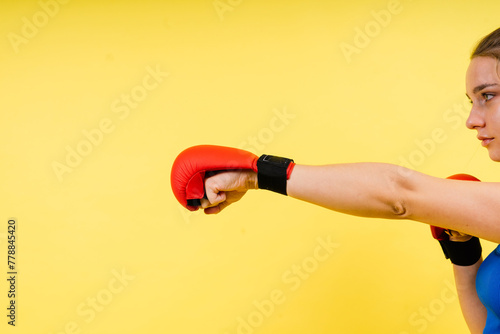 Woman boxer in gloves training on grey and yellow background © Ivan Zelenin