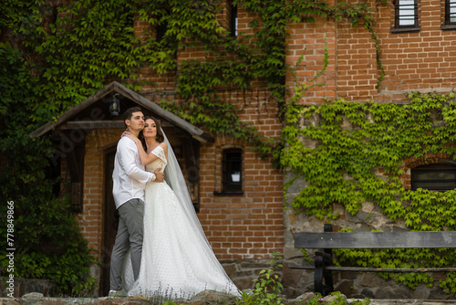 Romantic lovely newly married couple posing by the medieval castle on their wedding day photo