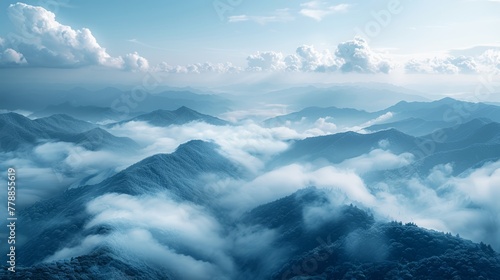  A stunning aerial shot of majestic mountains shrouded by clouds in the foreground against a serene backdrop of a clear blue sky dotted with fluffy white clouds