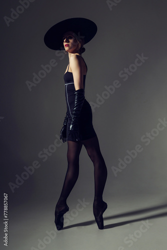 ballerina in the style of fashion total black in a dress, hat and gloves poses ballet elements