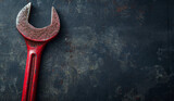 Vintage red wrench on a grungy textured surface.