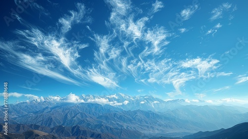  A stunning panorama of mountain peaks against a backdrop of brilliant azure sky and fluffy white clouds dotted throughout