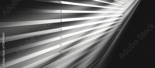 The sunlight filters through the wooden blinds, casting a pattern of tints and shades on the metal floor. The monochrome sky adds to the darkness of the scene in this black and white photograph