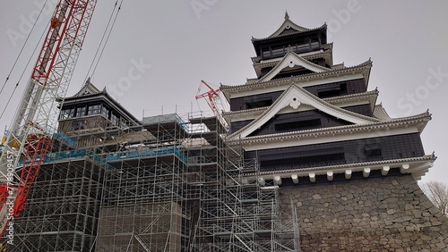 Kumamoto, Japan - 01.26.2020: Kumamoto Castle under reconstruction work after the 2016 earthquake with scaffolds and a crane in sight under a cloudy sky photo
