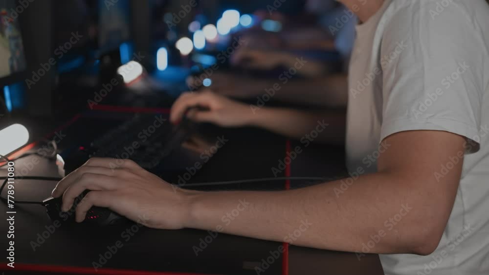 Player uses professional gaming mouse and PC keyboard with RGB lighting, mat. Cyber team in computer club. Skill. Esports tournament. Gamers play video game. Multiplayer online real-time strategy Player uses professional gaming mouse and PC keyboard with RGB lighting, mat. Cyber team in computer club. Skill. Esports tournament. Gamers play video game. Multiplayer online real-time strategy