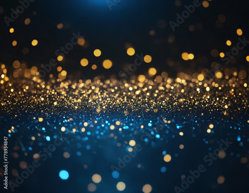 Close-up of gold and blue glitter haphazardly scattered on a dark background, creating a blurred effect. The glitter shimmers and reflects light, adding lustre to the dark background.