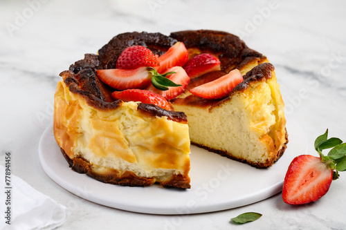 Basque san sebastian cheesecake on a marble background with strawberries