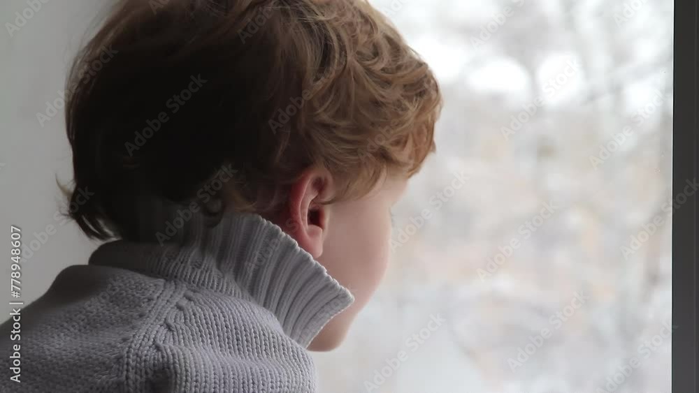 First Snow. Boy looking out the window at the falling snow First Snow. Boy looking out the window at the falling snow