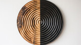 Abstract image of a circular sculpture with contrasting halves, one in natural wood tones and the other painted black, against a white textured wall.