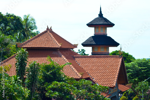 View Of Tiled Roof Of Buddhist Temple Building And Multi-Tiered Top Of Pagoda Soaring Amidst The Trees Of The Garden photo