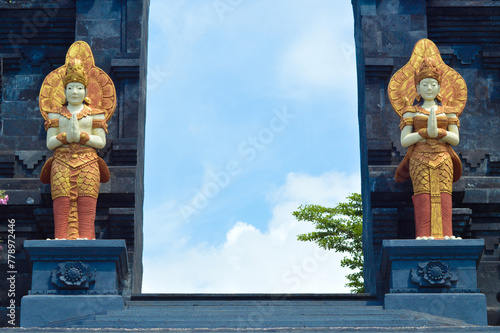 Low Angle View Of Male And Female Guardian Statue In Front Of The Entrance Gate To Main Area Of Buddhist Temple At Banjar Tegeha, Buleleng, Bali, Indonesia photo