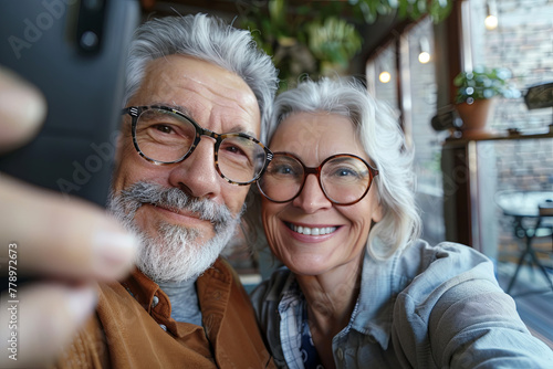 Wonderful sincere cheerful couple of gray haired mature smiling people taking selfie portrait on phone. Today's active retirees are enjoying life. A man with a gray beard and a woman in glasses