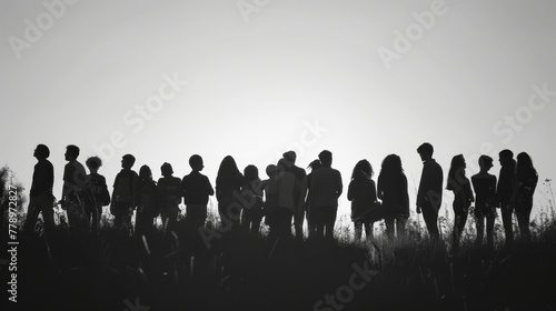 A group of people are standing on a hill, with some of them holding backpacks. The image has a sense of unity and togetherness, as the people are all gathered together in a group