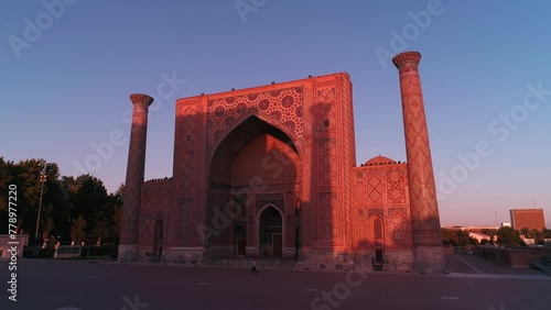 A drone flies near a complex Bibi-Khanym Mosque in Samarkand, Uzbekistan. The building is illuminated by the pink dawn light. Cloudless morning. photo