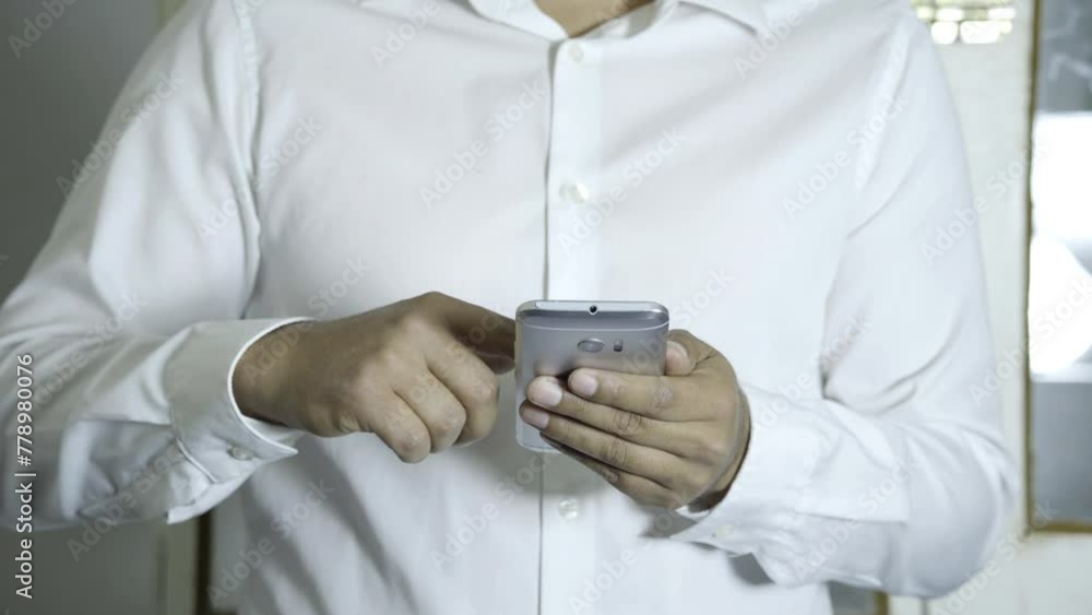 man wearing a white shirt reading and using a smartphone, concentrated reading news man wearing a white shirt reading and using a smartphone, concentrated reading news