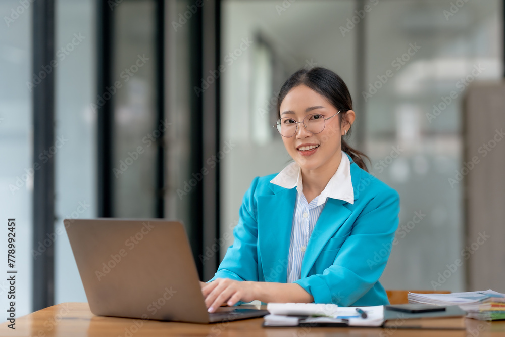 Asian businesswoman is sitting at a desk with a laptop in front of her Asian businesswoman is sitting at a desk with a laptop in front of her