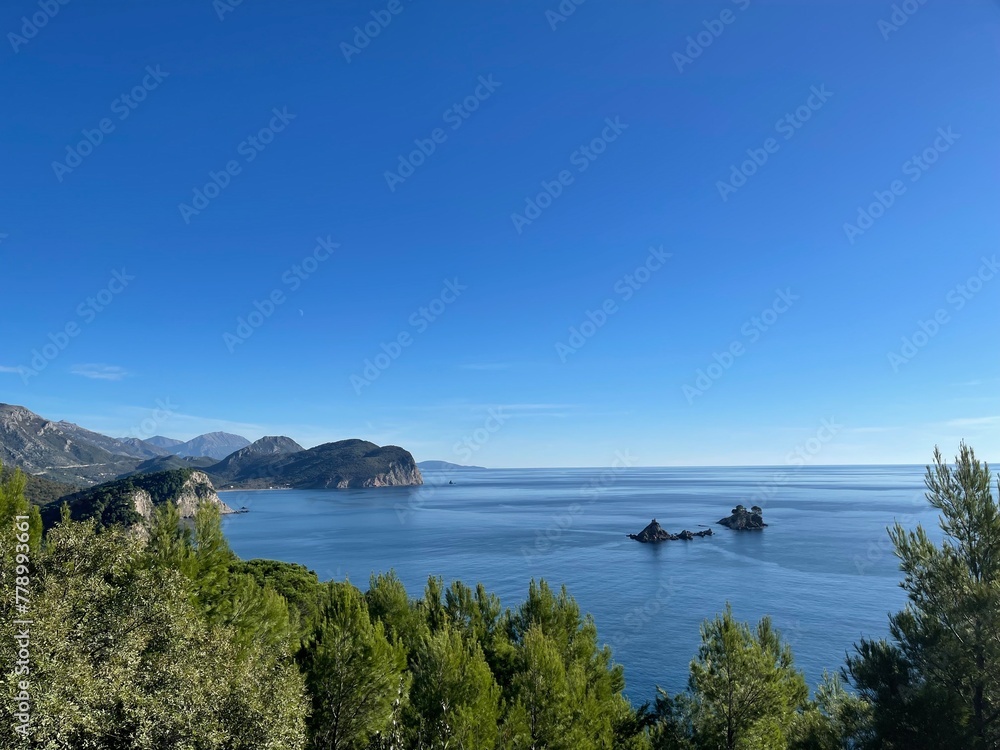 Pebble beach on Montenegrin coast with clear water and by summer day.