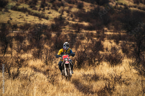 Professional enduro bike rider on action, front view of the motorcycle rider driving on the mountains