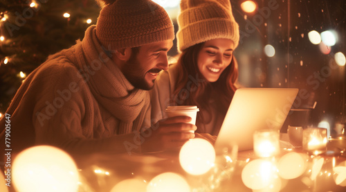 An European couple in a cafe in winter hat smiling with coffee cups and computers. Concepts of business and love. Can be used as blog and news image