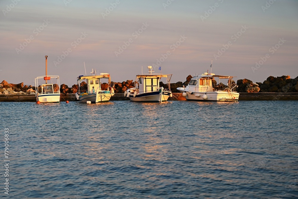 Small fishing boats in the harbor at sunset. Concept for travel and summer vacation. Greece-island of Corfu.