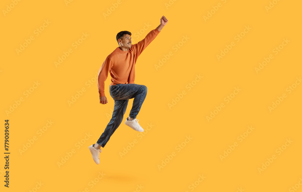 Jumping man with raised fist on yellow