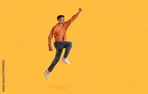 Jumping man with raised fist on yellow © Prostock-studio