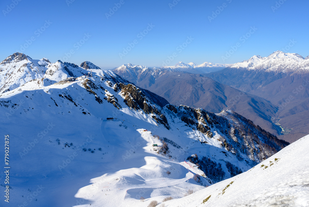 Caucasian mountains covered with snow with a small ski resort building on the slope