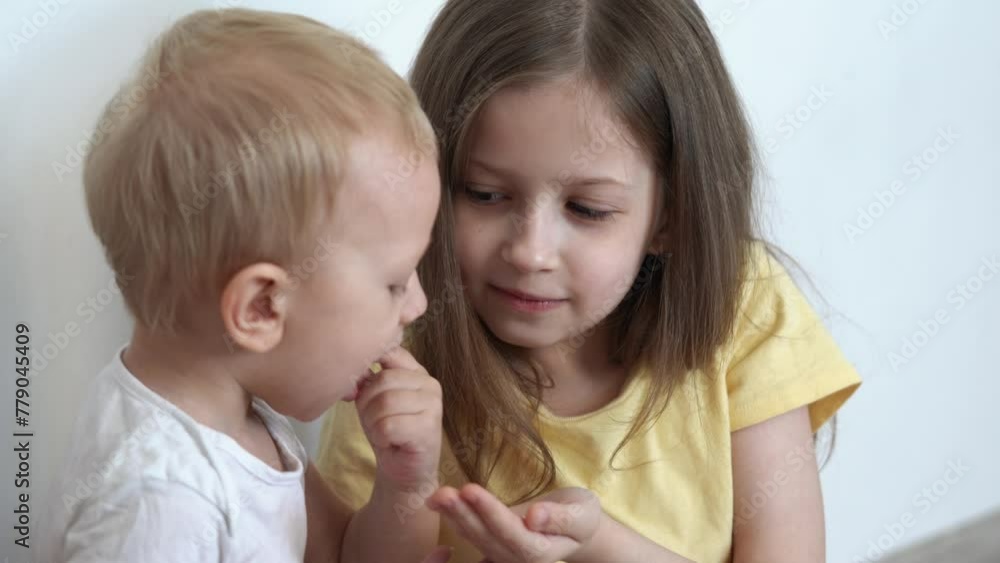 A girl treats her little brother to cookies A girl treats her little brother to cookies
